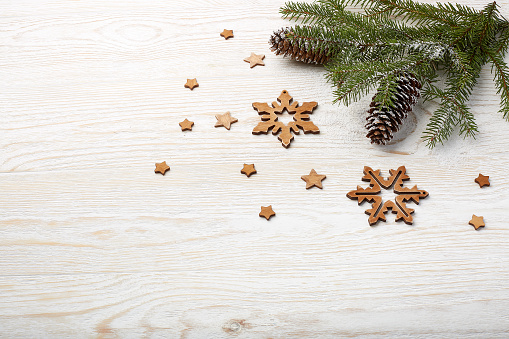 Light wooden background with fir branches, christmas decorations and cones. New Year and Christmas