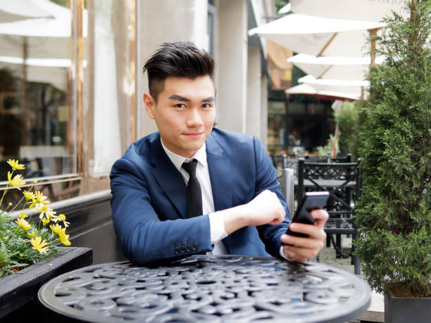 retrato de un hombre de negocios guapo en traje azul con teléfono móvil en un restaurante al aire libre, cerca de vista de la parte superior del cuerpo. modelo chino hipster hombre atractivo. - china shanghai business people fotografías e imágenes de stock