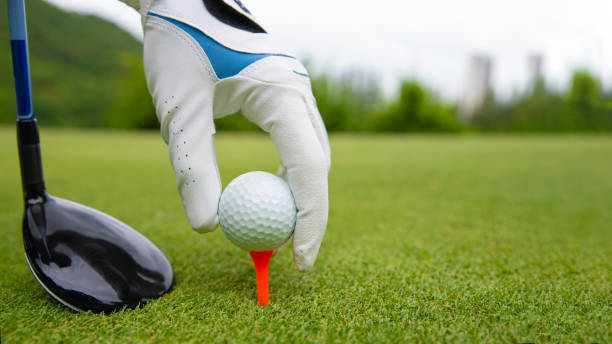 mano poniendo pelota de golf en tee en el campo de golf - tee fotografías e imágenes de stock