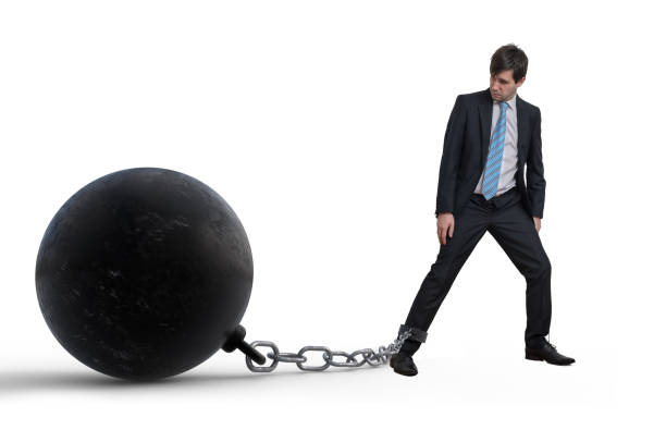 Young businessman has chained big metal ball to his leg. Isolated on white background. Young businessman has chained big metal ball to his leg. Isolated on white background. dragging photos stock pictures, royalty-free photos & images