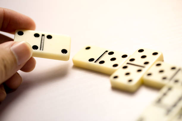 Playing dominoes on a white wooden table.