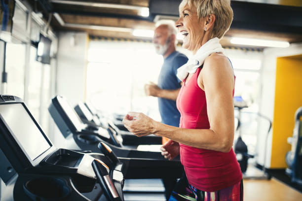 starsi ludzie biegający na bieżni maszynowej w klubie fitness gym - senior adult healthy lifestyle athleticism lifestyles zdjęcia i obrazy z banku zdjęć