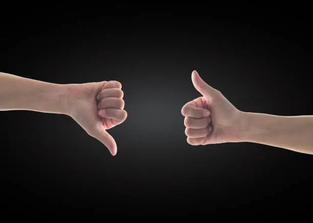 Photo of Like - unlike hand with thumb up - down symbolic people gesture isolated on black background with clipping path