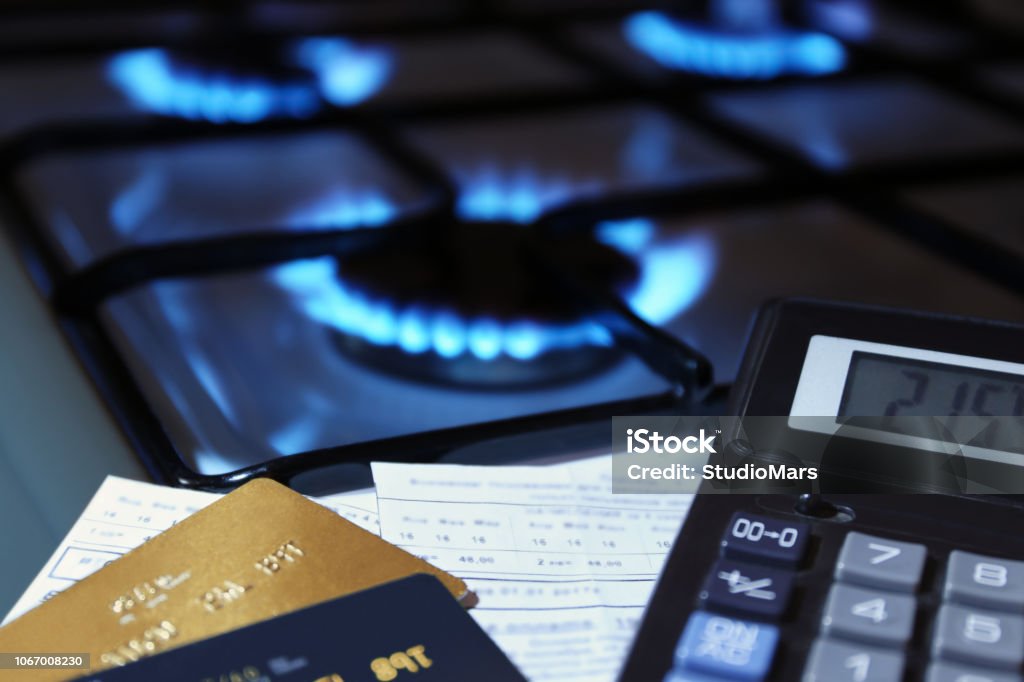 bank cards and a calculator on the background of a gas stove bank cards and a calculator on the background of a burning  gas stove Gas Stock Photo