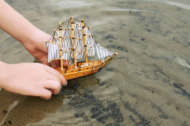 istock child playing with a toy sailing ship by the river, hand closeup 1067008802
