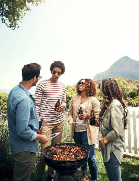 Gathered together for a chilled weekend Shot of a group of friends having a barbecue together south african braai stock pictures, royalty-free photos & images