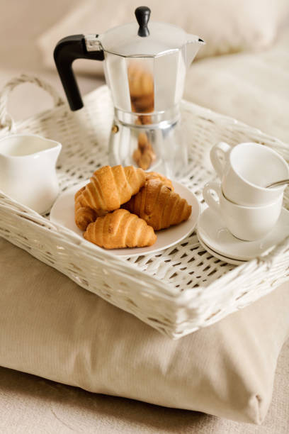 istock Breakfast in bed. On a white wicker tray there is a coffee maker, coffee white cups and croissants. 1067016212