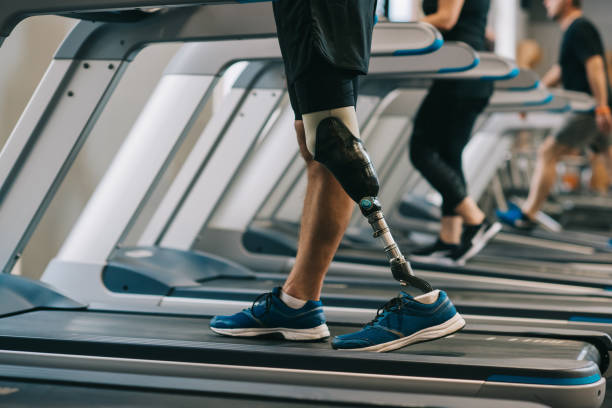 cropped shot of man with artificial leg walking on treadmills at gym with other people cropped shot of man with artificial leg walking on treadmills at gym with other people prosthetic equipment stock pictures, royalty-free photos & images