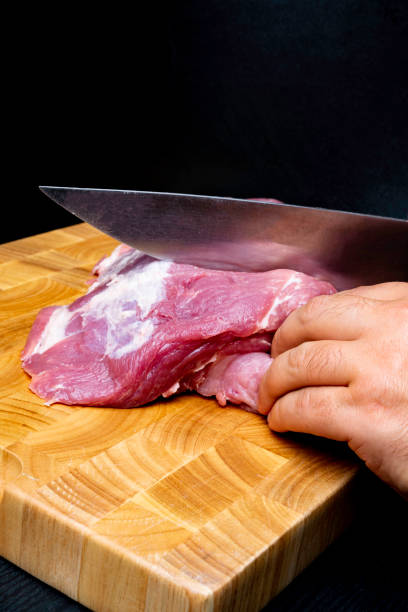 istock Butcher cutting pork meat on kitchen on wooden board 1067022108