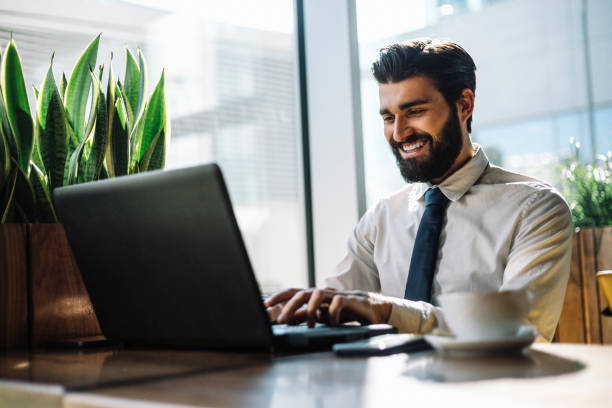 istock Attractive young businessman drinks coffee and using laptop 1067024428