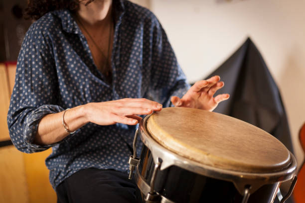 Percussion instruments and musicology concept. Detail of a percussionist male hands while playing bongos on a rehearsal studio with natural light. guiro stock pictures, royalty-free photos & images