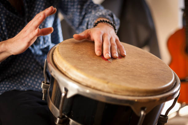 Percussion instruments and musicology concept. Detail of a percussionist male hands while playing bongos on a rehearsal studio with natural light. guiro stock pictures, royalty-free photos & images