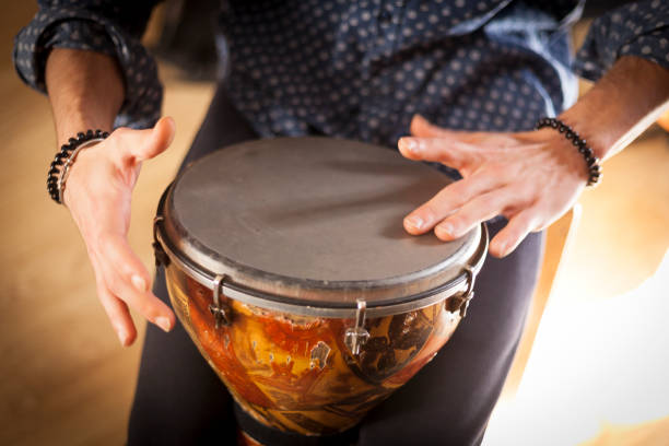 Percussion instruments and musicology concept. Detail of a percussionist male hands while playing timbal on a rehearsal studio with natural light. guiro stock pictures, royalty-free photos & images