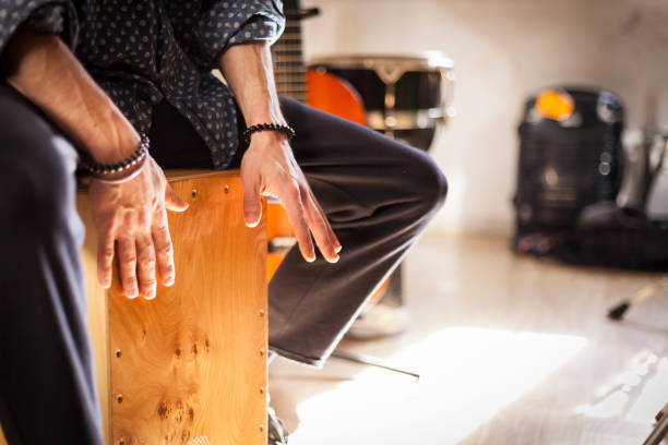 Flamenco drumbox being played by percussionist. Detail of a percussionist male hands while playing flamenco drumbox on a rehearsal studio with drums and music stuff on the background with natural light. Flamenco instruments and musicology concept. rumba photos stock pictures, royalty-free photos & images