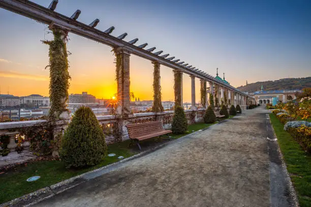 Budapest, Hungary - Beautiful sunrise at Varkert Bazaar with bench, Statue of Liberty at background and autumn foliage
