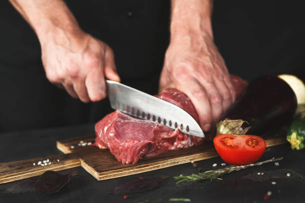 istock Chef cutting filet mignon on wooden board 1067041180