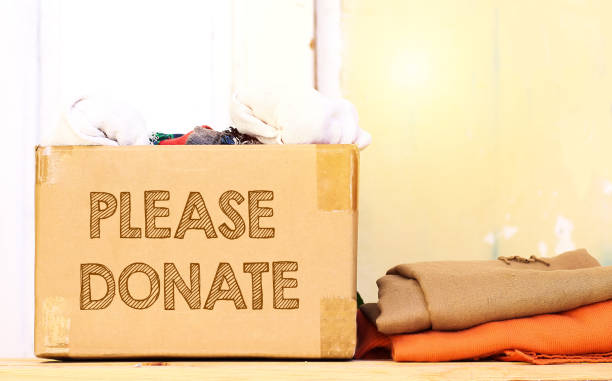 istock clothes in carton box on wood table for donation, coat drive concept, please donate text 1067044300