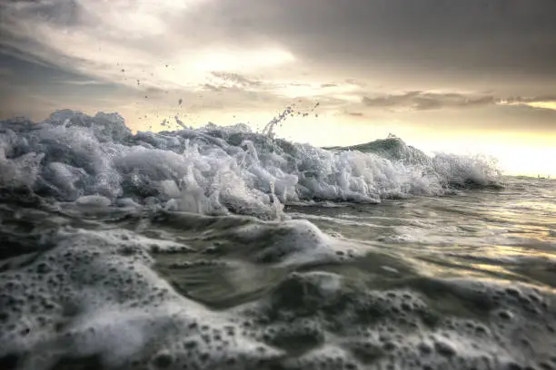 Closeup of ocean waves crashing on the shore during sunrise
