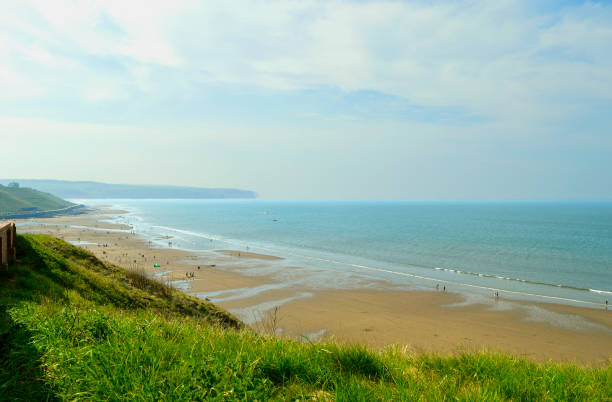 Tourists on Whitby beach West Cliff in North Yorkshire