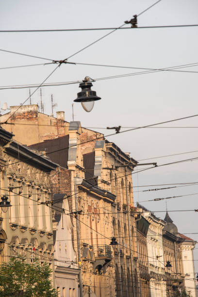 KRAKOW, POLAND - NOVEMBER 13, 2018:  Exterior view of a row of colorful buildings and tram wire and street lamps hanging overhead in  Krakow, Poland.