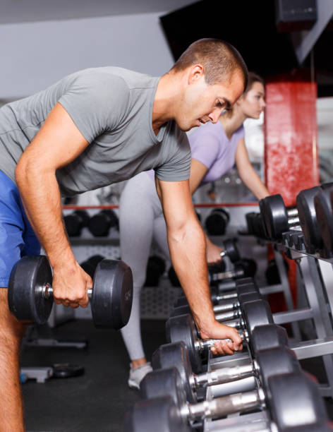 istock Cheerful man and girl choosing dumbbells 1067057314