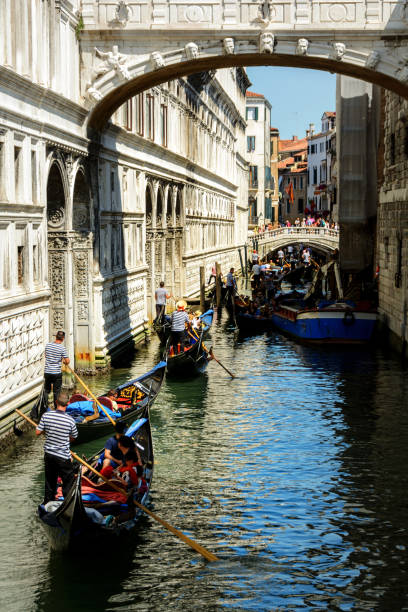 Gondola ride in Venice, Italy Venice, Italy - July 9, 2018 : Several black gondolas moving through the water canal with the tourists inside. Venice is a one of the most famous travel destination in the world, a city in northeastern Italy and the capital of the Veneto region. Gondola is a traditional, flat-bottomed Venetian rowing boat, well suited to the conditions of the Venetian lagoon.Their primary role today is to carry tourists on rides. venice italy grand canal honeymoon gondola stock pictures, royalty-free photos & images