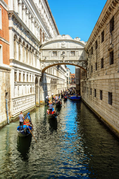 Gondola ride in Venice, Italy Venice, Italy - July 9, 2018 : Several black gondolas moving through the water canal with the tourists inside. Venice is a one of the most famous travel destination in the world, a city in northeastern Italy and the capital of the Veneto region. Gondola is a traditional, flat-bottomed Venetian rowing boat, well suited to the conditions of the Venetian lagoon.Their primary role today is to carry tourists on rides. venice italy grand canal honeymoon gondola stock pictures, royalty-free photos & images