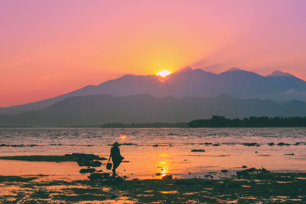 Beautiful sunrise at the beach with a mountain background Full frame shots a sunrise landscape in Gili Trawangan beach, with a silhouette of the mountain and an unrecognizable silhouette of a fisherman gili trawangan stock pictures, royalty-free photos & images