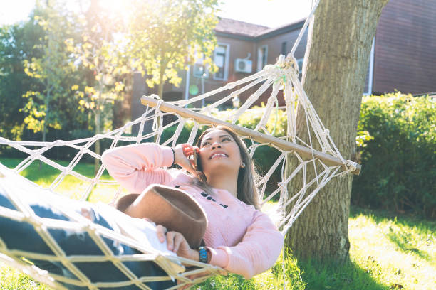 istock Young Asian woman talking on mobile phone and lying down on a hammock 1067071672