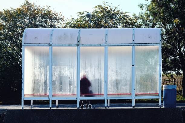 Bus shelter Old lady waiting for the bus in a fogged up bus shelter bus shelter stock pictures, royalty-free photos & images