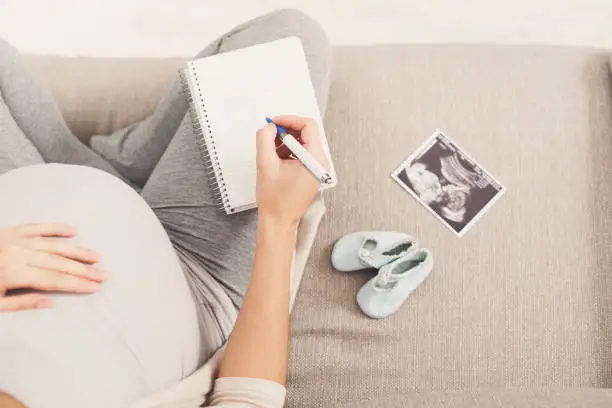 Photo of Pregnant woman writing names for her baby