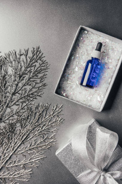 istock top view of christmas gift box with serum and decorated branches on silver 1067094150