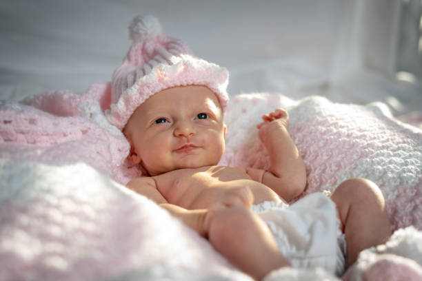 Newborn baby girl in a pink hat on a pink blanket stock photo