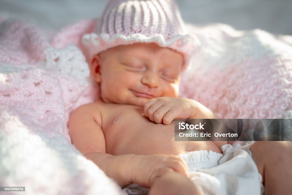 Newborn baby girl in a pink hat on a pink blanket Photo of a three week old baby girl Babies Only Stock Photo