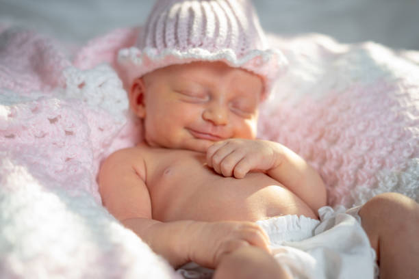 Newborn baby girl in a pink hat on a pink blanket stock photo