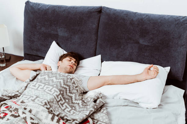 istock selective focus of man stretching in bed during morning time at home 1067101580