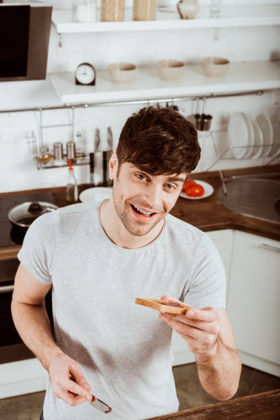 istock high angle view of young man having eating toast with jam on breakfast at kitchen 1067105668