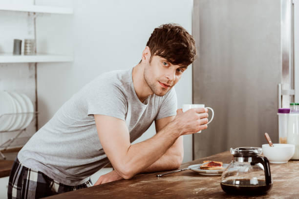 istock man drinking coffee at table with toasts and coffee pot in kitchen at home 1067106744