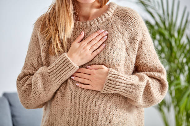 young woman with heart problem holding chest. - peito imagens e fotografias de stock