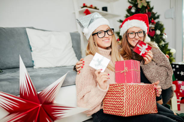 Best friends/sister sitting near Christmas tree and enjoying Christmas eve/ New year's. stock photo
