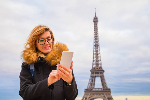 istock Girl using cellphone with Paris city background and Eiffel tower. 1067110072