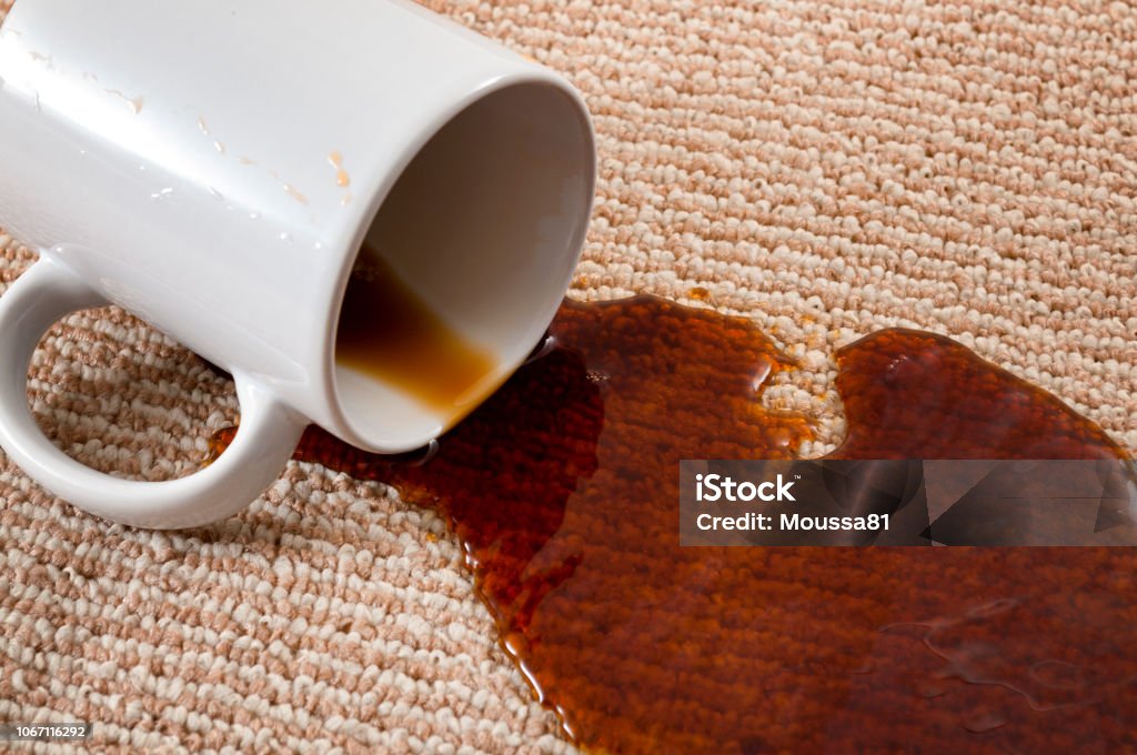Home mishap, stained carpet, and domestic accident concept with close up of a spilled cup of coffee leaving a stain on the brown carpet Coffee - Drink Stock Photo
