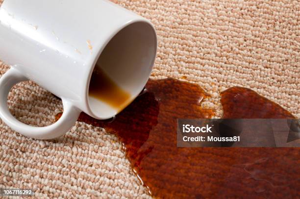 Home Mishap Stained Carpet And Domestic Accident Concept With Close Up Of A Spilled Cup Of Coffee Leaving A Stain On The Brown Carpet Stock Photo - Download Image Now
