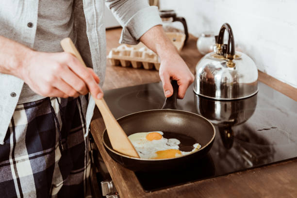 istock partial view of man cooking scrambled eggs on frying pan in kitchen 1067117380