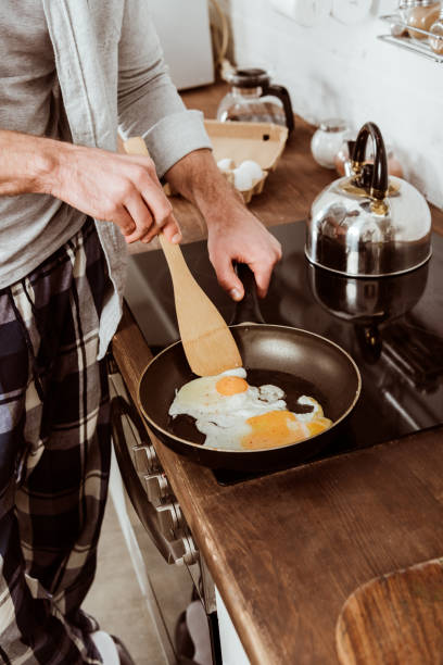istock cropped image of man cooking scrambled eggs on frying pan in kitchen 1067117390