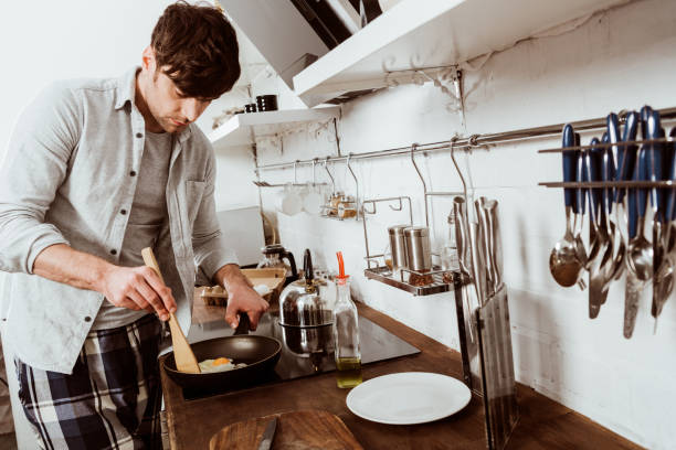istock selective focus of man cooking scrambled eggs on frying pan in kitchen 1067117398