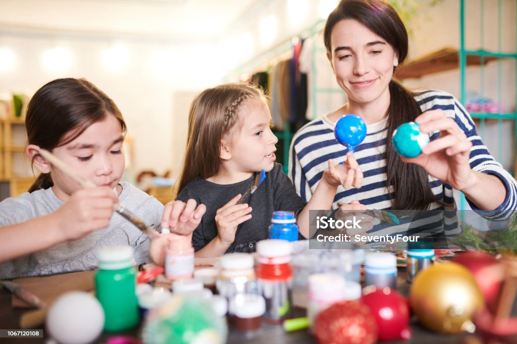 Family  Making Handmade Ornaments Portrait of two little children making handmade Christmas decorations in crafting class with smiling female teacher Child Stock Photo
