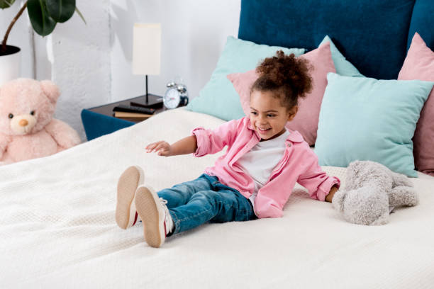 istock Playful african american kid on the bed with teddy bear 1067123040