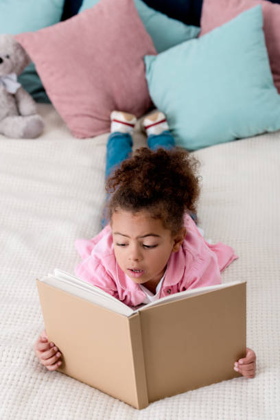 istock Surprised  African american kid laying on the bed and reading book 1067123236
