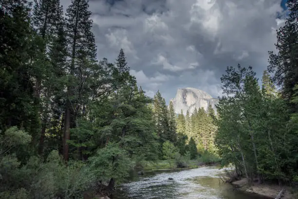 Half Dome and the Merced River, in California's Yosemite National park as a thunderstorm rolls in